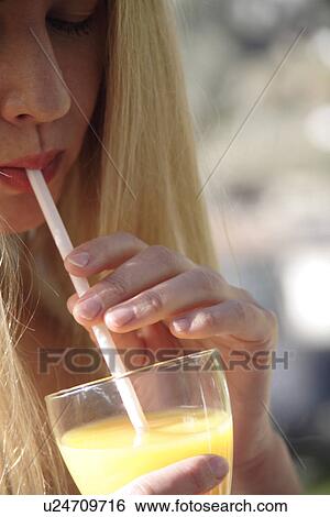 Young blond woman drinking orange juice with straw, close up View Large Photo Image Stock Photograph - Young blond woman drinking orange juice with straw, close up. Fotosearch