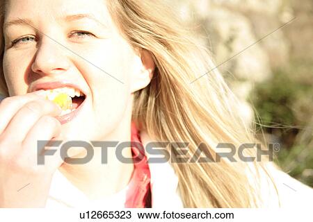 Young blond woman eating orange segment, portrait View Large Photo Image Stock Image - Young blond woman eating orange segment, portrait. Fotosearch