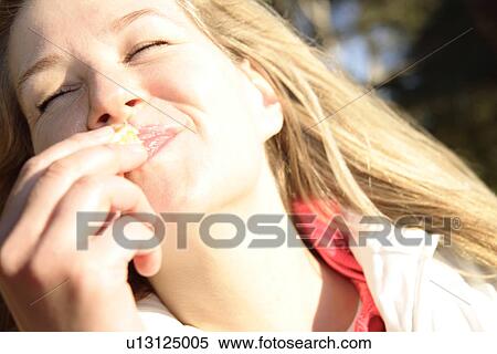 Stock Photography - Young blond woman enjoying orange with closed eyes, portrait. Fotosearch