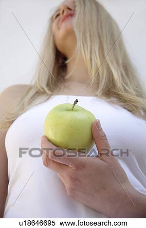 Young blond woman holding apple, close up View Large Photo Image Stock Photography - Young blond woman holding apple, close up. Fotosearch