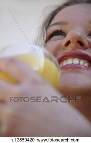 Young blond woman holding glass of orange juice, view from below View Large Photo Image Stock Image - Young blond woman holding glass of orange juice, view from below. Fotosearch