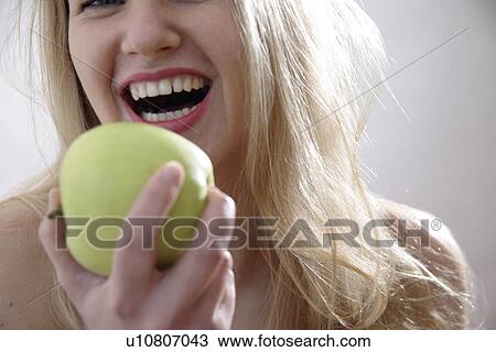 Young blond woman holding green apple, close up View Large Photo Image Stock Image - Young blond woman holding green apple, close up. Fotosearch