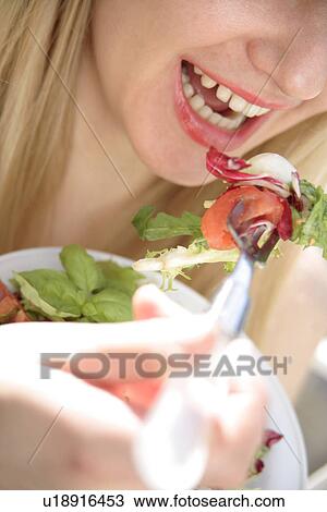 Stock Image - Young woman eating mixed salad, close up. Fotosearch