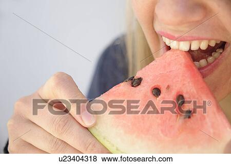 Stock Photo - Young woman eating watermelon, close up. Fotosearch
