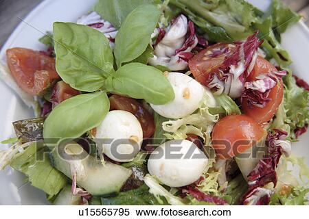 Stock Photography - Fresh salad decorated with mozzarella cheese and basil leaves, overhead view. Fotosearch