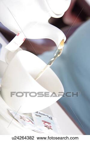 Stock Image - Pouring tea into cup, close up. Fotosearch