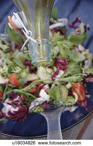 Stock Photograph - Preparing fresh salad: adding olive oil. Fotosearch