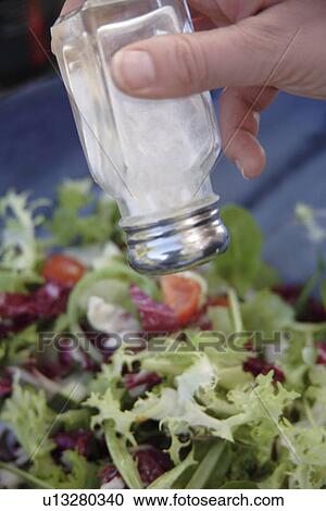 Stock Image - Preparing fresh salad: adding salt. Fotosearch
