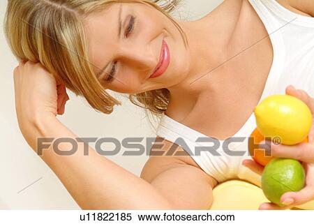 Stock Photography - Woman lying, holding citrus fruit. Fotosearch