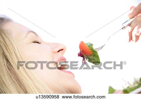 Young blond woman about to eat spoonful of salad, profile, close up View Large Photo Image Stock Photo - Young blond woman about to eat spoonful of salad, profile, close up. Fotosearch