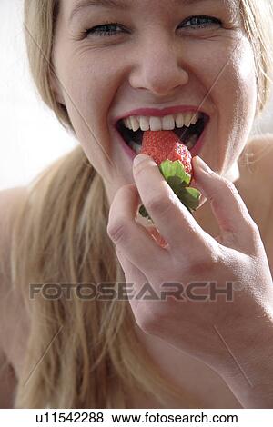 Young blond woman biting in strawberry, portrait View Large Photo Image Stock Photo - Young blond woman biting in strawberry, portrait. Fotosearch