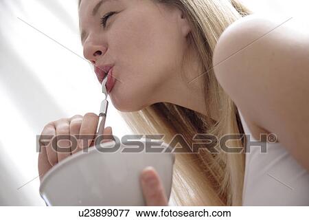 Young blond woman eating bowl of cereals, laughing, close up View Large Photo Image Stock Photo - Young blond woman eating bowl of cereals, laughing, close up. Fotosearch