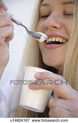 Young blond woman eating pure yogurt, close up View Large Photo Image Stock Photo - Young blond woman eating pure yogurt, close up. Fotosearch