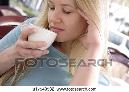 Stock Image - Young blond woman enjoying cup of coffee with eyes closed, portrait. Fotosearch