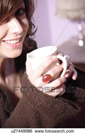 Stock Photograph - Young brunette woman holding cup of coffee, close up. Fotosearch