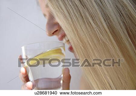 Woman drinking glass of water with slice of lemon in it, face profile, close up View Large Photo Image Stock Image - Woman drinking glass of water with slice of lemon in it, face profile, close up. Fotosearch
