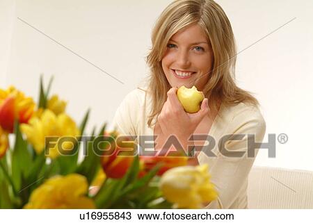 Woman eating apple, flowers in foreground View Large Photo Image Stock Image - Woman eating apple, flowers in foreground. Fotosearch