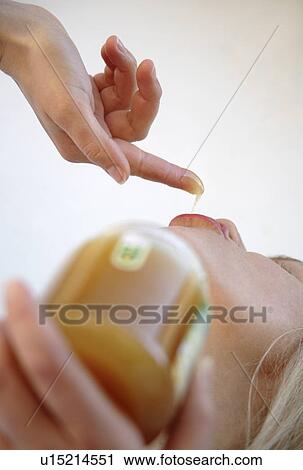Stock Image - Woman licking honey from finger, close up. Fotosearch