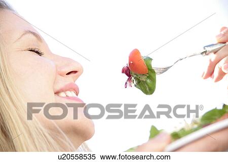 Young blond woman about to eat spoonful of salad, profile, close up View Large Photo Image Stock Photography - Young blond woman about to eat spoonful of salad, profile, close up. Fotosearch