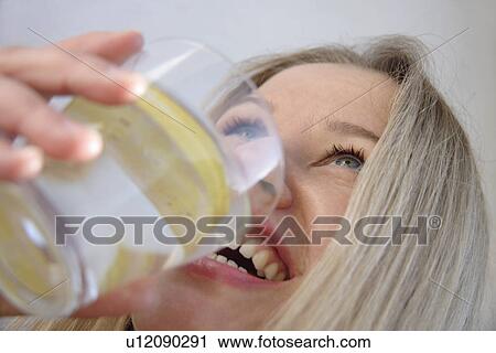 Young blond woman drinking glass of water with lemon slice, side view, close up View Large Photo Image Stock Image - Young blond woman drinking glass of water with lemon slice, side view, close up. Fotosearch