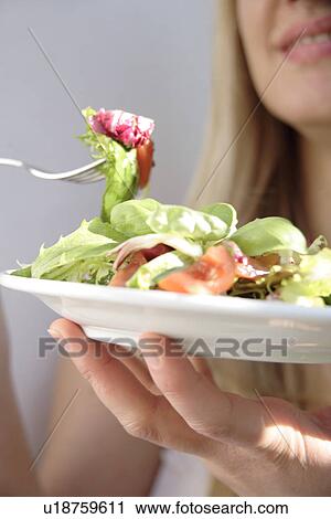 Stock Image - Young woman eating mixed salad, close up. Fotosearch
