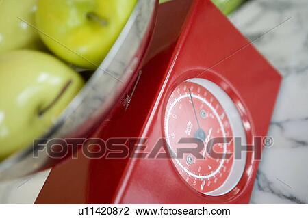 Stock Image - Green apples on kitchen scale, close up. Fotosearch