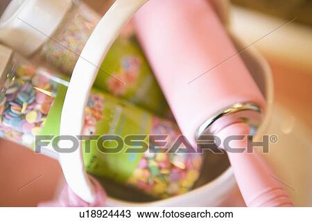 Stock Image - Pink rolling pin in a basket with sprinkles, close up. Fotosearch