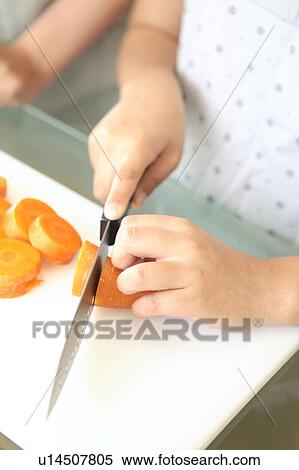 Hand holding knife cutting a carrot View Large Photo Image Stock Photography - Hand holding knife cutting a carrot. Fotosearch