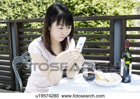 Stock Image - Woman looking at cell phone on the terrace. Fotosearch