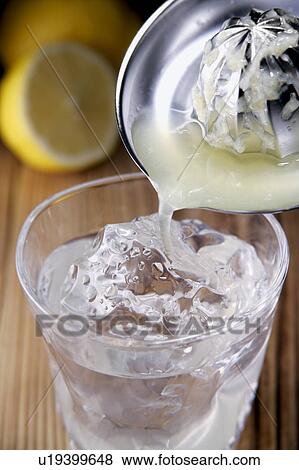 Stock Photo - Lemon juice poured into glass of shochu. Fotosearch