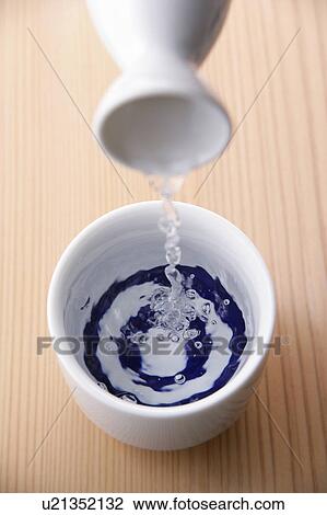 Stock Image - Sake pouring into cup. Fotosearch