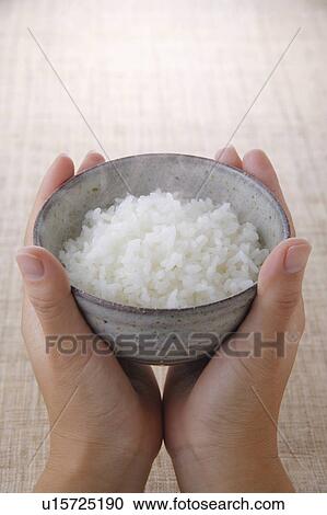 Stock Image - A woman holding a bowl of rice. Fotosearch