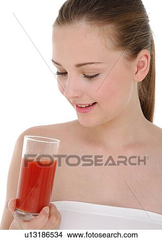 Picture - Close-up of a young woman holding a glass of juice and smiling. Fotosearch