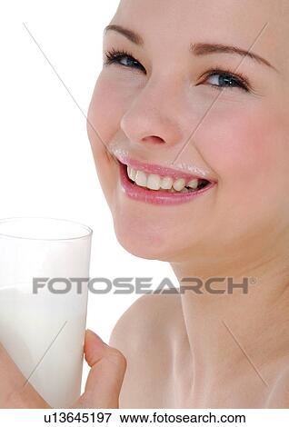 Stock Photo - Close-up of a young woman holding a glass of milk and smiling. Fotosearch