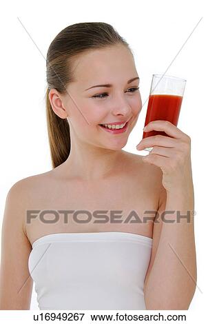 Stock Photo - Close-up of a young woman holding a glass of juice and grining. Fotosearch