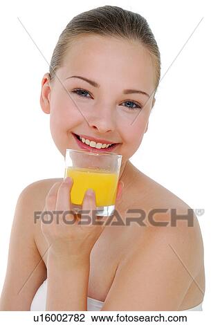 Stock Image - Portrait of a young woman holding a glass of orange juice and grining. Fotosearch