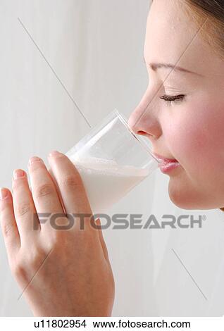 Side profile of a young woman drinking a glass of milk View Large Photo Image Picture - Side profile of a young woman drinking a glass of milk. Fotosearch