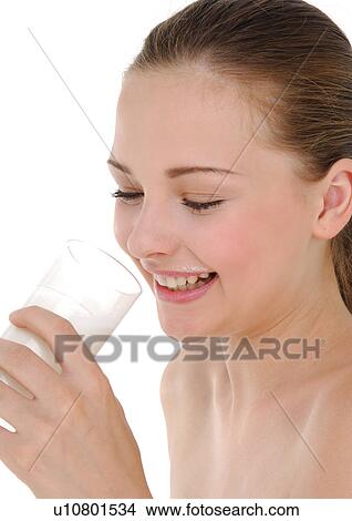 Picture - Side profile of a young woman holding a glass of milk and grining. Fotosearch