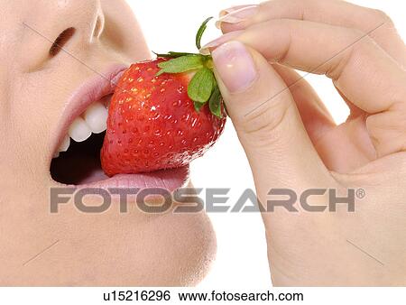 Stock Photograph - Close-up of a young woman eating a strawberry. Fotosearch