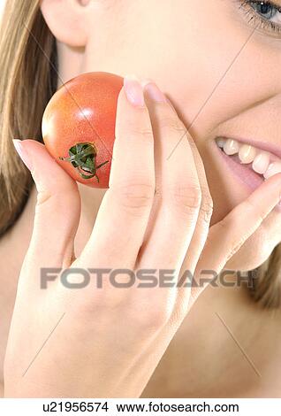 Close-up of a young woman holding a tomato and grining View Large Photo Image Picture - Close-up of a young woman holding a tomato and grining. Fotosearch
