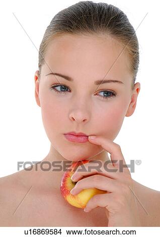Picture - Close-up of a young woman holding an apple and thinking. Fotosearch