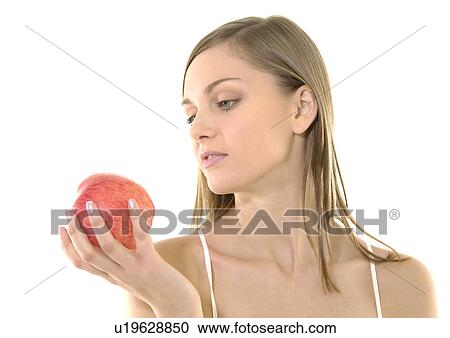Stock Image - Close-up of a young woman holding an apple. Fotosearch