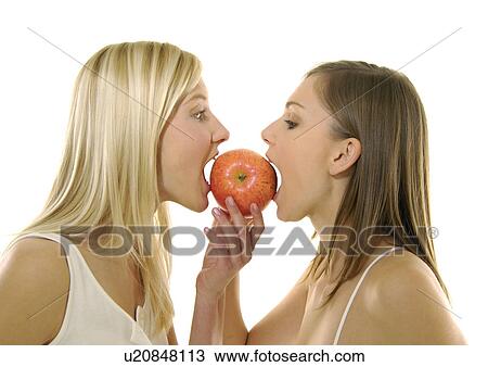 Stock Image - Close-up of two young women eating an apple. Fotosearch
