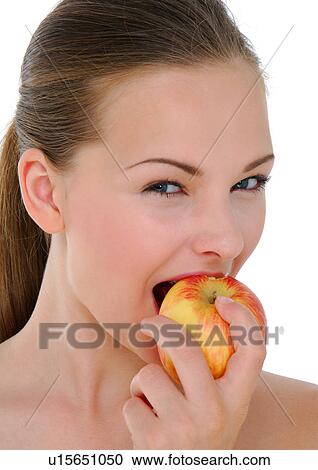 Stock Image - Portrait of a young woman eating an apple. Fotosearch