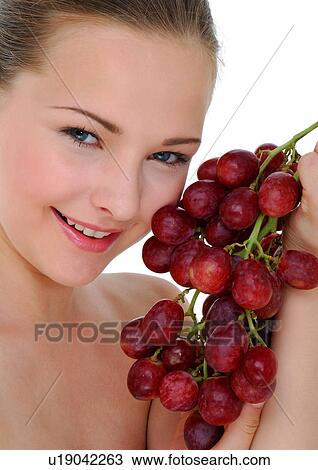 Portrait of a young woman holding a bunch of red grapes View Large Photo Image Stock Image - Portrait of a young woman holding a bunch of red grapes. Fotosearch