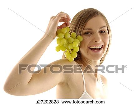 Stock Photo - Portrait of a young woman holding a bunch of grapes and laughing. Fotosearch