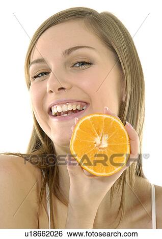 Stock Photograph - Portrait of a young woman holding a cross section of a orange and grining. Fotosearch