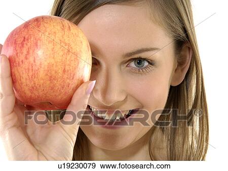 Stock Photo - Portrait of a young woman holding an apple and grining. Fotosearch