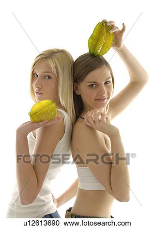 Stock Image - Portrait of two young women holding starfruits. Fotosearch