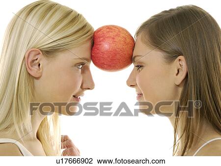 Side profile of two young women balancing an apple with their foreheads View Large Photo Image Stock Image - Side profile of two young women balancing an apple with their foreheads. Fotosearch